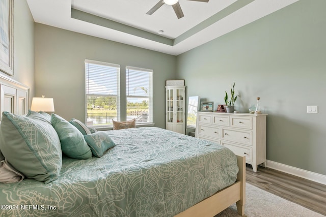 bedroom featuring hardwood / wood-style floors, ceiling fan, and a tray ceiling