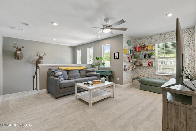 living room featuring light carpet, ceiling fan, and a textured ceiling