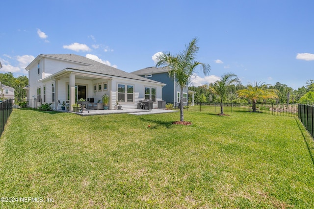 rear view of property featuring central AC unit, a patio area, and a lawn