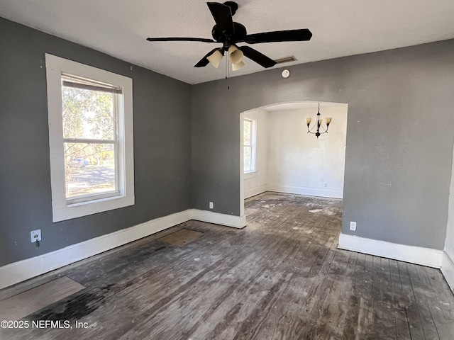 empty room with dark wood-type flooring and ceiling fan with notable chandelier