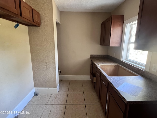 kitchen with light tile patterned flooring, sink, and a textured ceiling