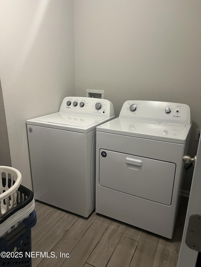 laundry area featuring wood-type flooring and separate washer and dryer