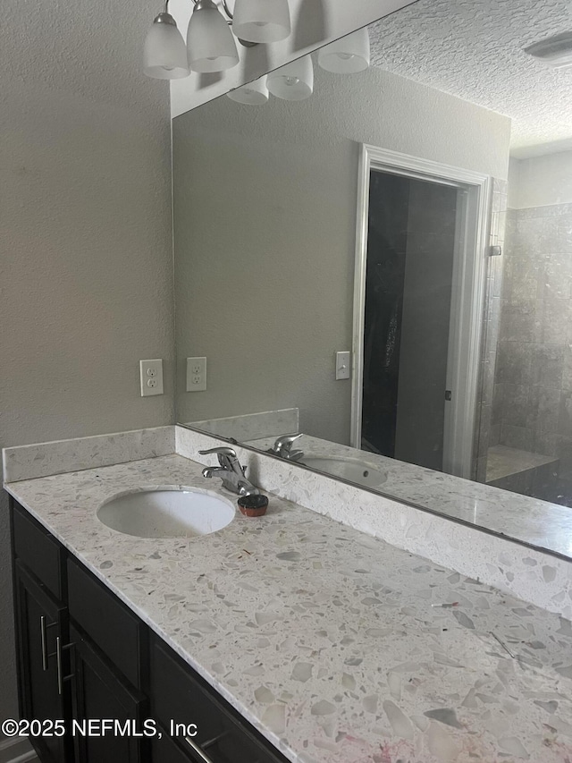 bathroom with vanity, an enclosed shower, and a textured ceiling