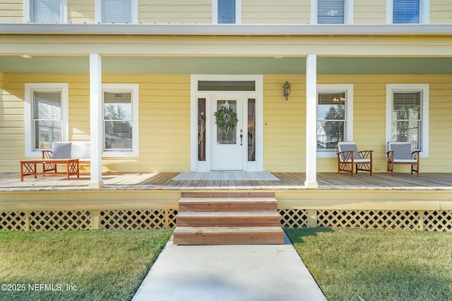 view of exterior entry featuring a porch and a yard