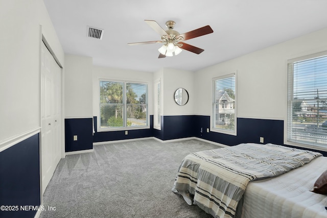 bedroom featuring light colored carpet, ceiling fan, and a closet