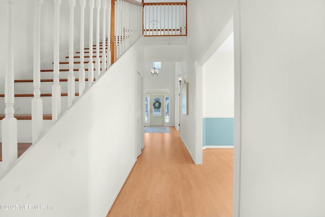 corridor with a towering ceiling and hardwood / wood-style floors