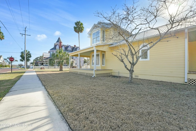 view of property exterior with covered porch and a lawn