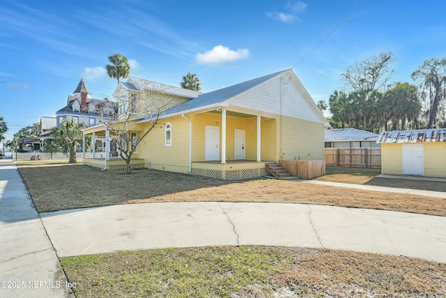 view of front of house with covered porch, a shed, and a front yard