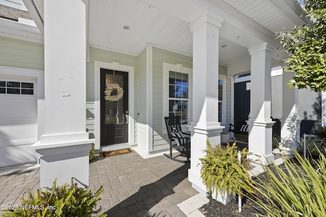 view of exterior entry featuring a garage and a porch