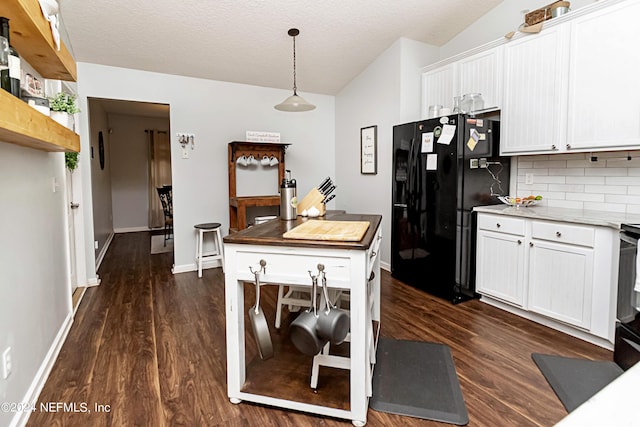 kitchen with white cabinetry, pendant lighting, dark wood-type flooring, and black fridge