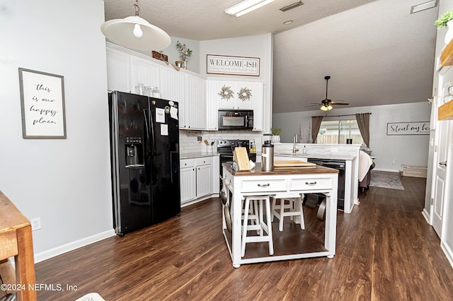 kitchen with lofted ceiling, butcher block counters, white cabinetry, hanging light fixtures, and black appliances