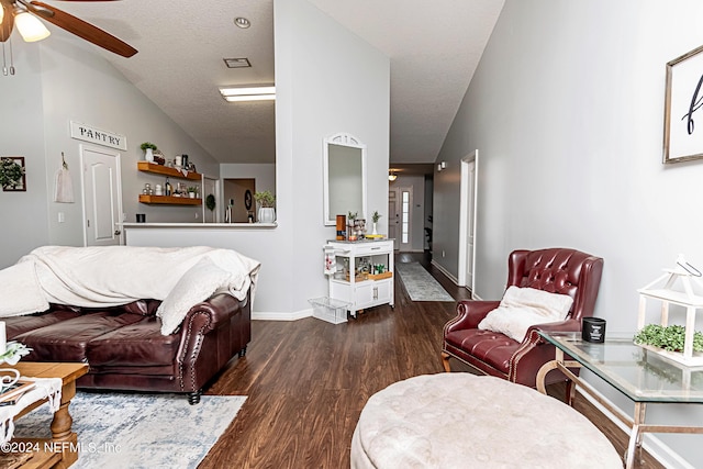 living room with ceiling fan, dark wood-type flooring, vaulted ceiling, and a textured ceiling