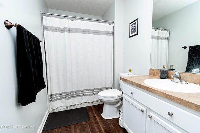 bathroom featuring wood-type flooring, toilet, a textured ceiling, and vanity