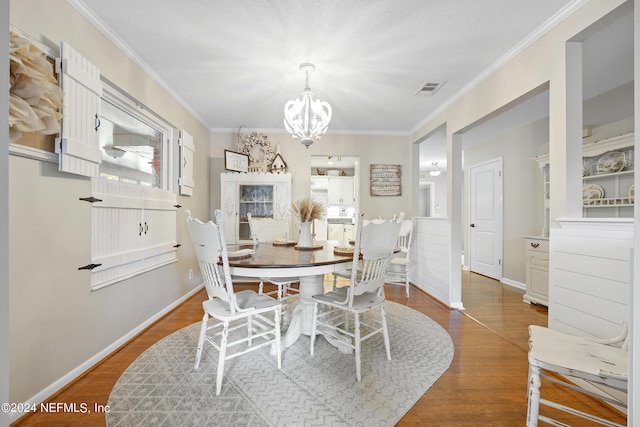 dining space featuring crown molding, hardwood / wood-style flooring, and a chandelier