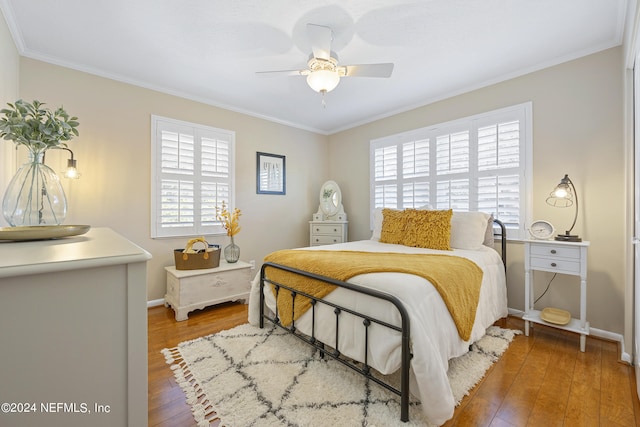 bedroom featuring hardwood / wood-style flooring, ceiling fan, crown molding, and multiple windows