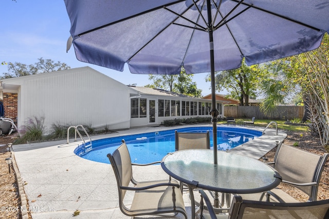 view of pool with a sunroom and a patio