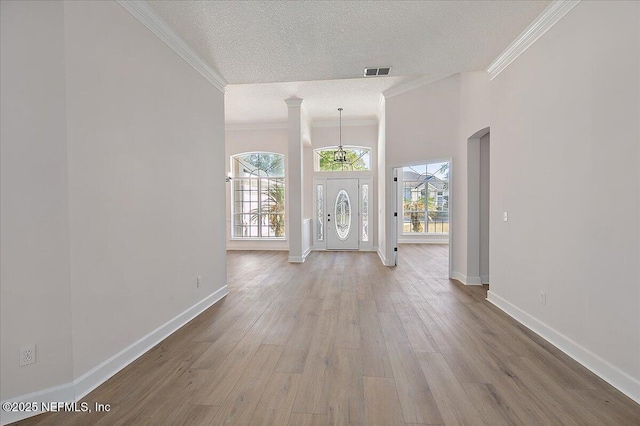 unfurnished living room with crown molding, hardwood / wood-style flooring, decorative columns, and a textured ceiling