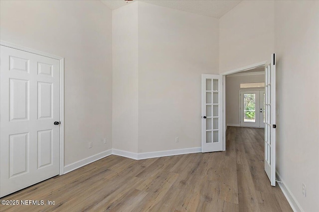 spare room with light hardwood / wood-style flooring, french doors, and a high ceiling