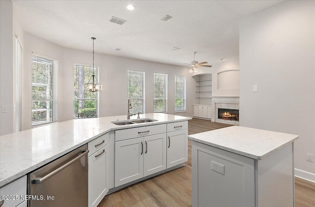 kitchen with sink, white cabinetry, decorative light fixtures, a center island with sink, and dishwasher