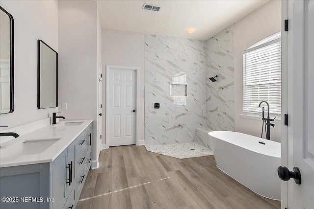 bathroom featuring vanity, shower with separate bathtub, wood-type flooring, and a textured ceiling