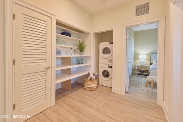 washroom featuring stacked washer / drying machine and light hardwood / wood-style floors