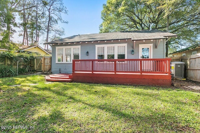 rear view of property with cooling unit, a deck, and a lawn