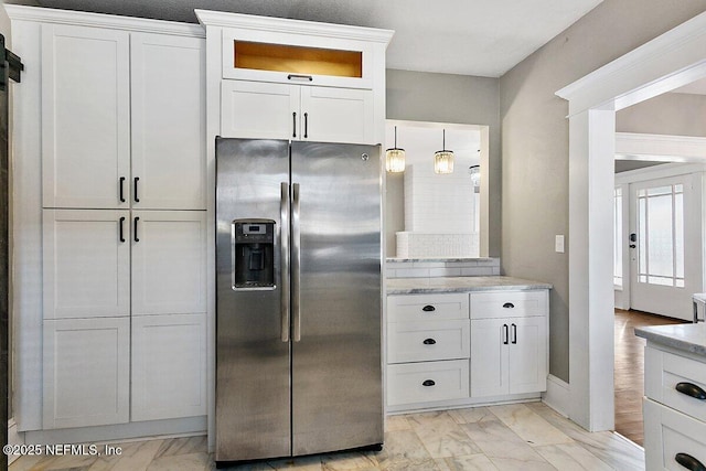 kitchen with white cabinetry, stainless steel fridge with ice dispenser, light stone countertops, and hanging light fixtures