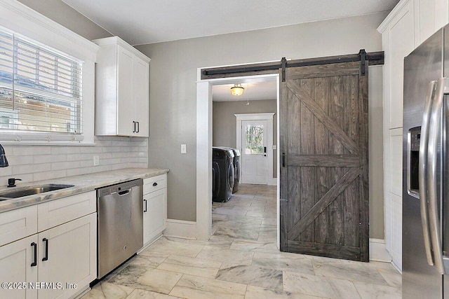 kitchen with stainless steel appliances, white cabinetry, a barn door, and sink