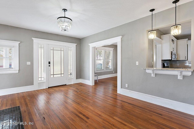 entrance foyer featuring plenty of natural light, dark hardwood / wood-style floors, and a chandelier