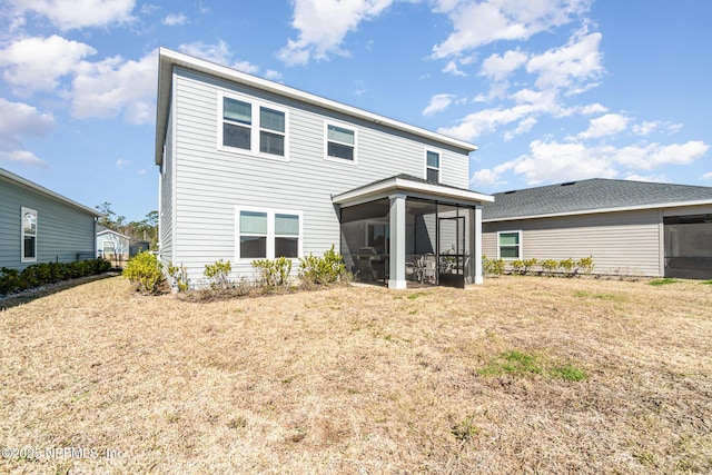 rear view of property with a lawn and a sunroom