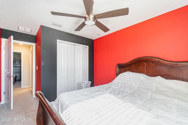 bedroom featuring light carpet, ceiling fan, a closet, and a textured ceiling