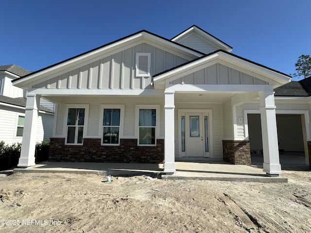 view of front of property with board and batten siding, brick siding, and a porch