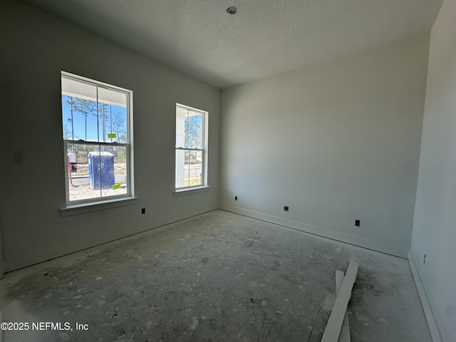 empty room featuring a textured ceiling and baseboards