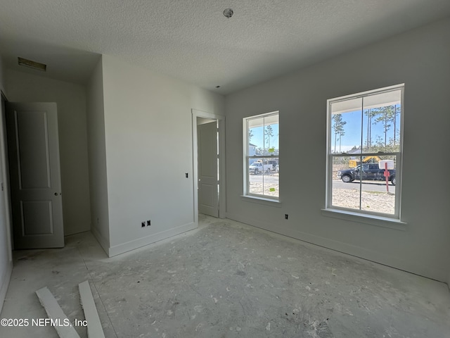 unfurnished bedroom featuring a textured ceiling and multiple windows