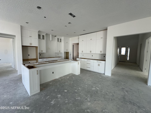 kitchen featuring glass insert cabinets, visible vents, white cabinets, and a center island