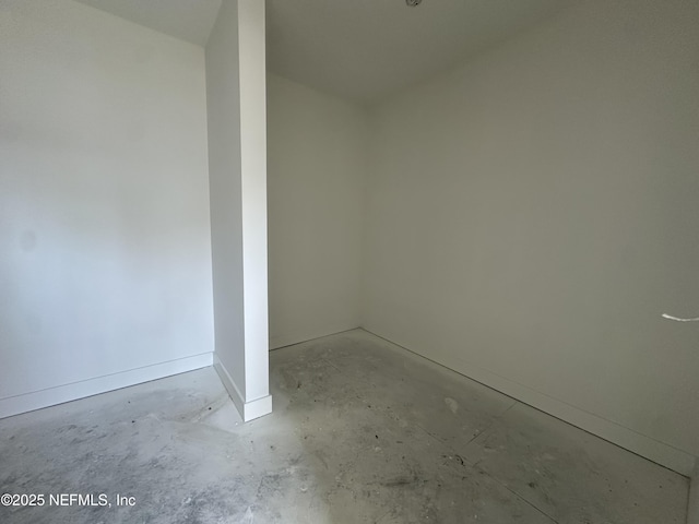 spare room featuring concrete floors and baseboards