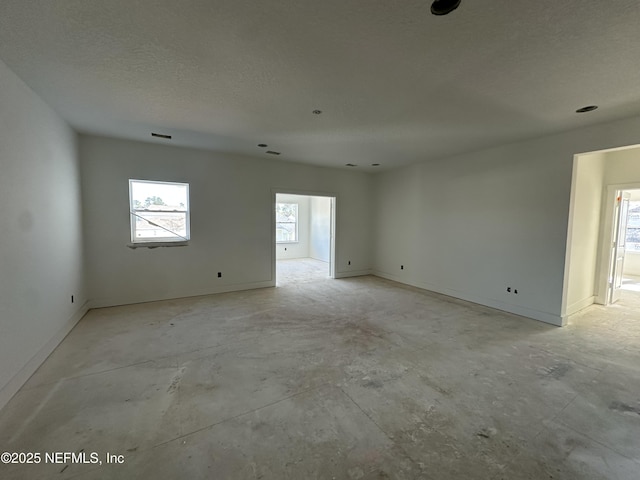 empty room featuring baseboards, visible vents, and a textured ceiling