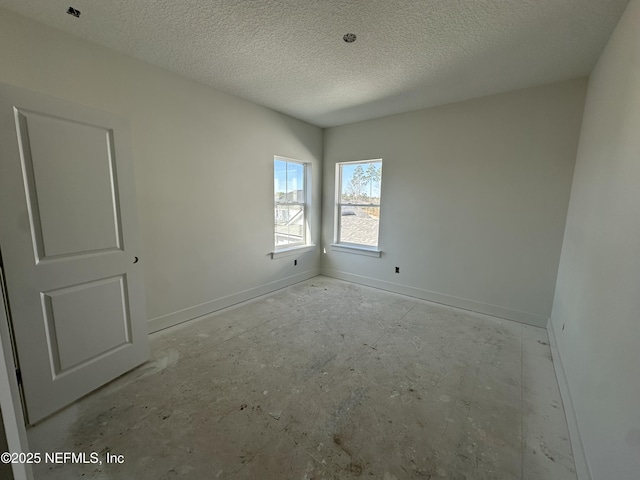 empty room featuring a textured ceiling and baseboards