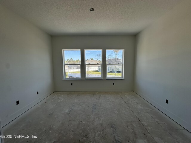 empty room with a textured ceiling and baseboards