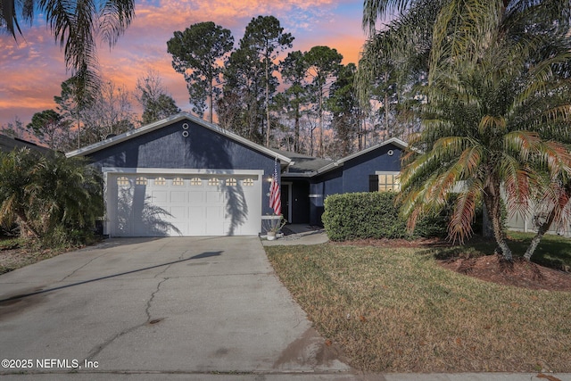 single story home featuring a garage and a lawn