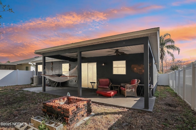 back house at dusk featuring central AC, ceiling fan, a fire pit, and a patio area