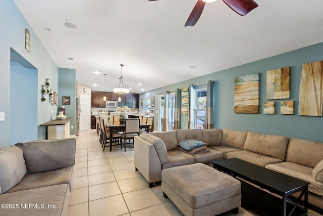 tiled living room with ceiling fan with notable chandelier