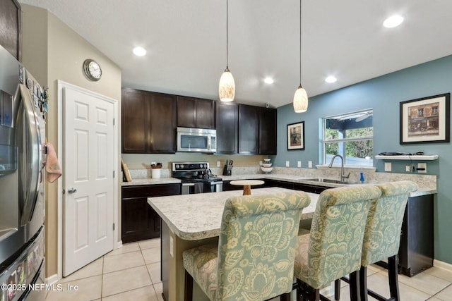 kitchen with sink, a breakfast bar, hanging light fixtures, stainless steel appliances, and a kitchen island