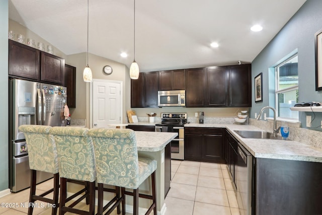 kitchen with sink, a center island, a kitchen breakfast bar, pendant lighting, and stainless steel appliances