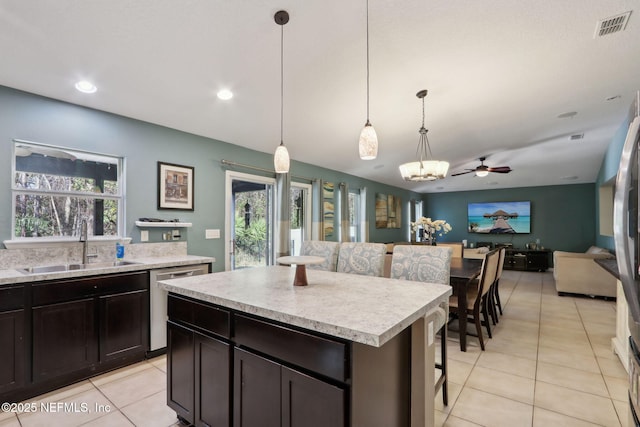 kitchen with light tile patterned floors, sink, dishwasher, a center island, and decorative light fixtures