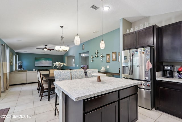 kitchen with stainless steel refrigerator with ice dispenser, a center island, dark brown cabinets, light tile patterned floors, and pendant lighting