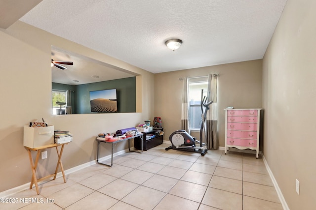 exercise room featuring light tile patterned floors, a textured ceiling, and a wealth of natural light