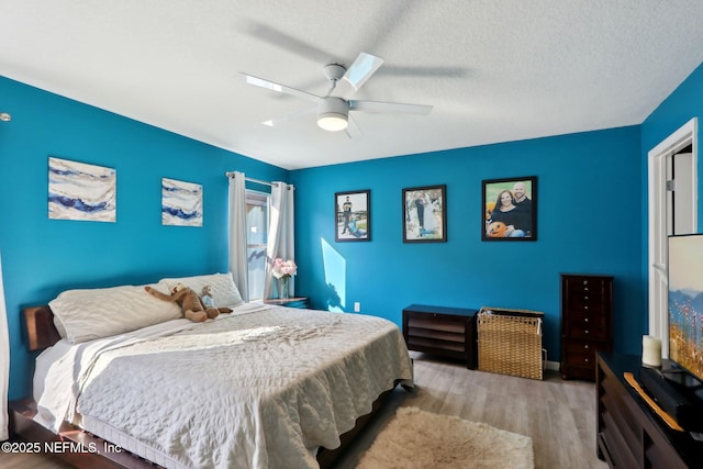 bedroom with ceiling fan, a textured ceiling, and light wood-type flooring