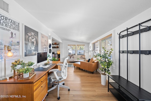 office area with vaulted ceiling and light wood-type flooring