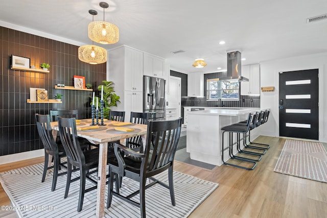 dining area featuring sink, tile walls, and light hardwood / wood-style flooring